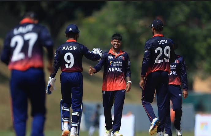 Four cricket players from Nepal celebrating a wicket, with one player extending a handshake in joy.